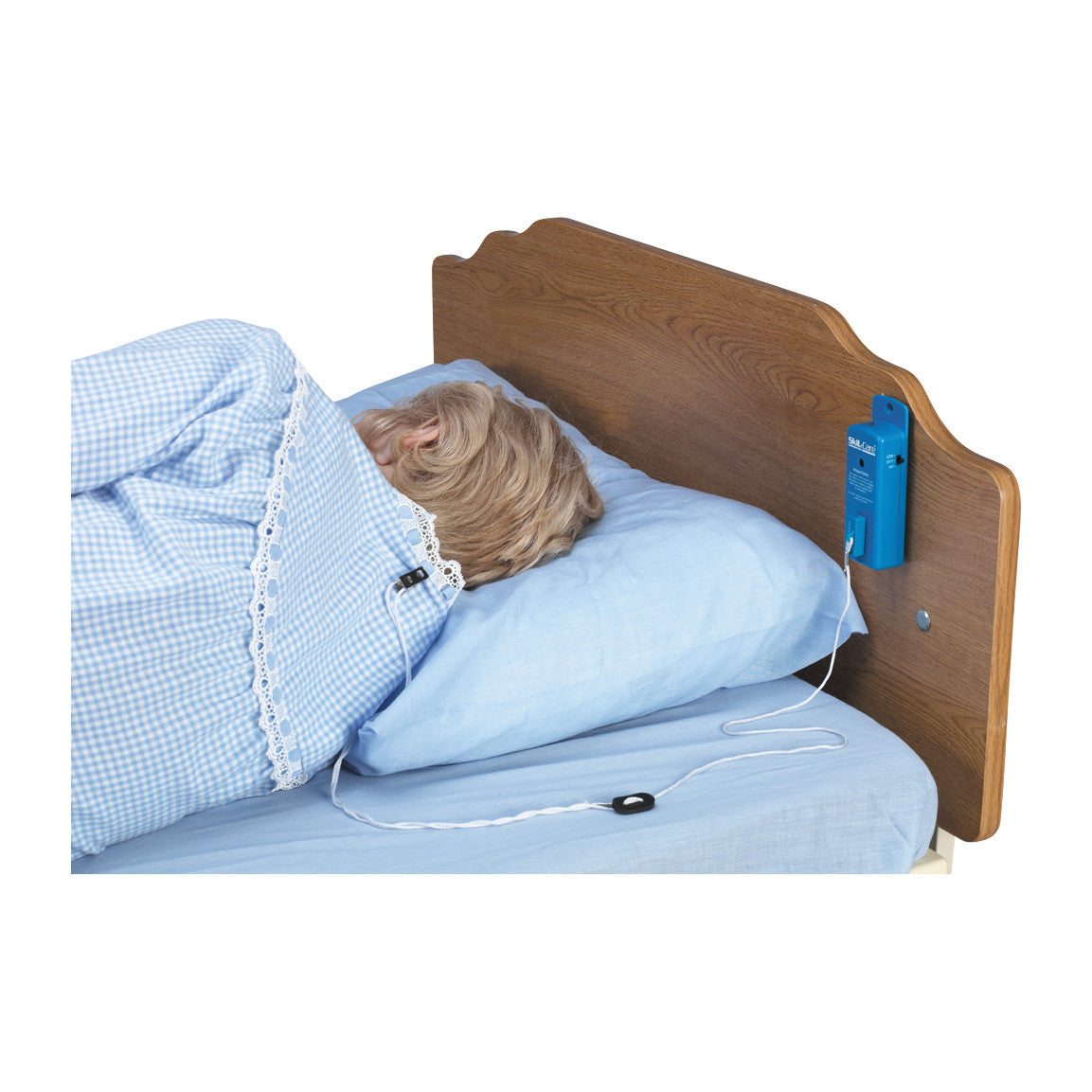 Person in bed with blue pajamas using a SkiL-Care Personal Alarm on headboard. A wire runs to a sensor on the pajamas.