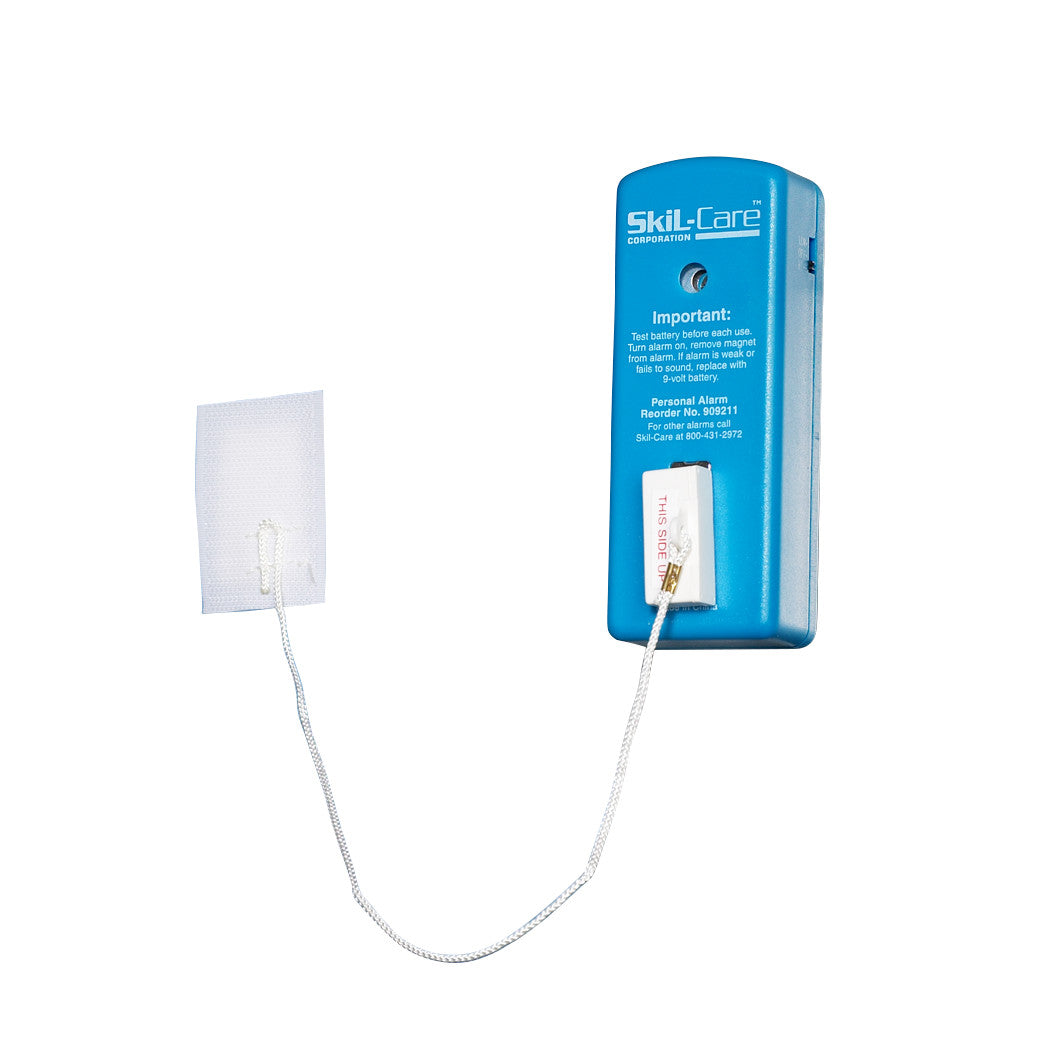 A blue SkiL-Care Window Alarm with a pull-cord connected to a white fabric pad. Instructions are printed on its surface.