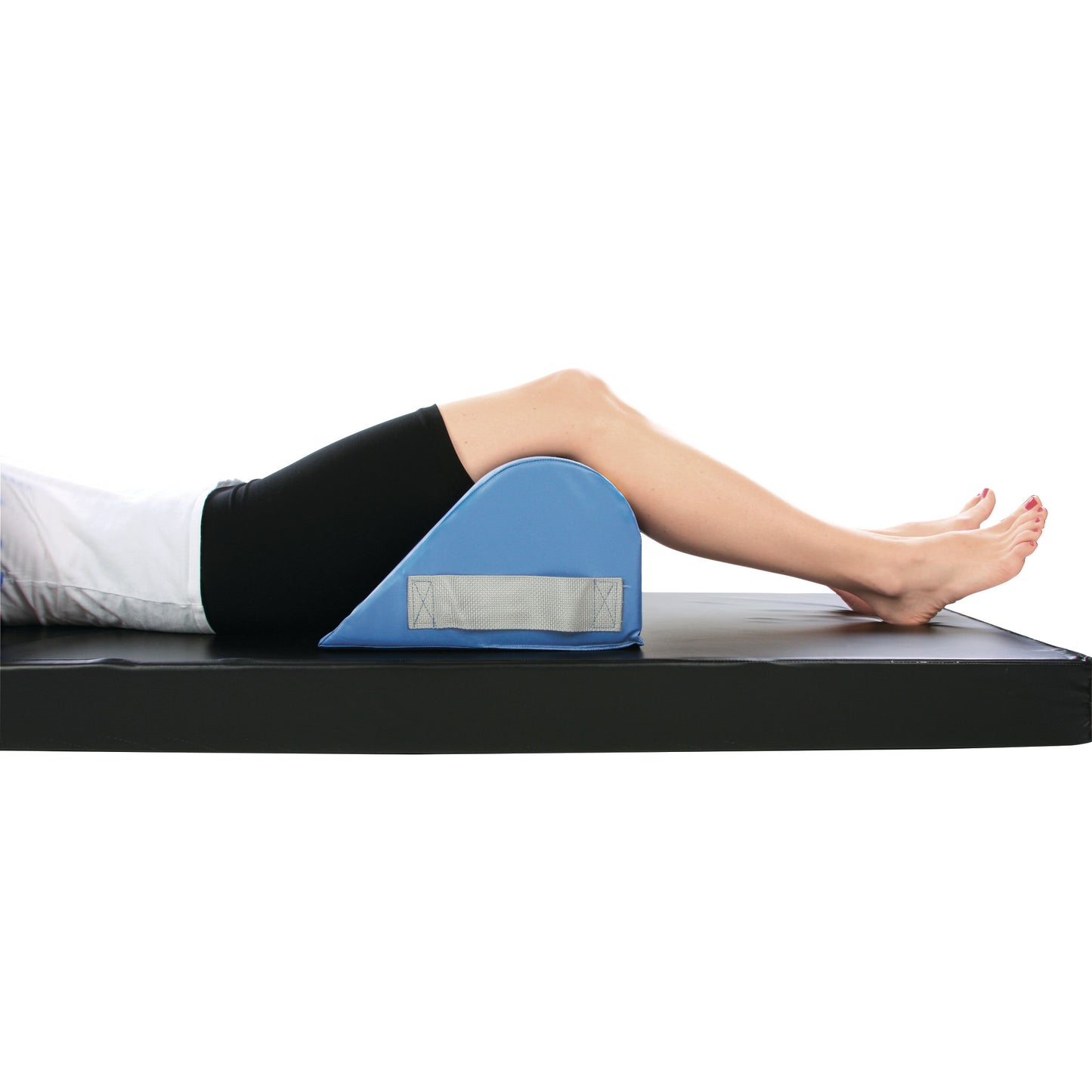 Person lying on a mat with knees supported by an AliMed Vinyl-Covered Standard Knee Bolster, colored blue with a gray strap.