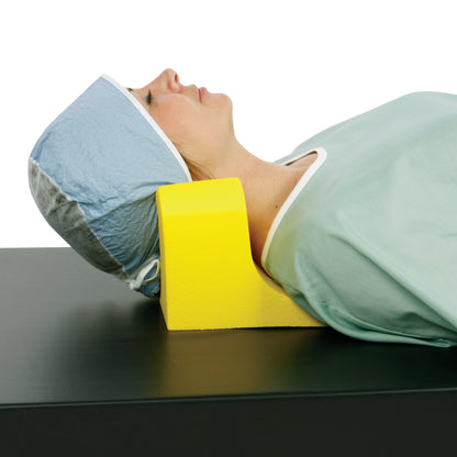 A person uses the AliMed Protecta-Coat Neck and Headrest, a yellow foam support, while lying on a black surface for comfort.