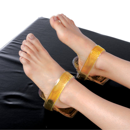 Feet resting in AliMed AliGel Comfort Heel Cup, Pair, featuring transparent gel straps on a black surface.