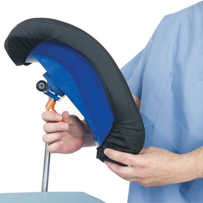 A person adjusts an AliMed Knee Crutch, featuring a blue support with a black cushion, mounted on a metal pole.