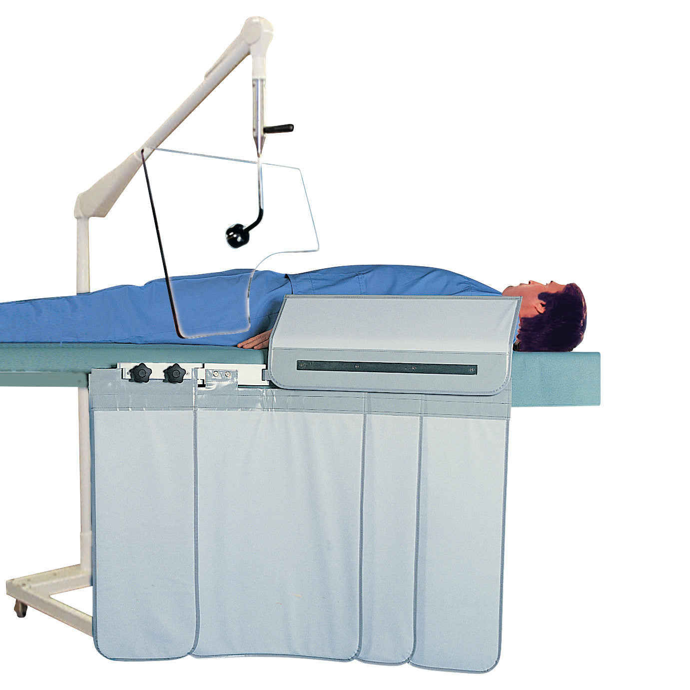 A person lies under an "Adjust-A-Height Pivoting Over-Table Barrier" with blue drapes, used for privacy or medical procedures.