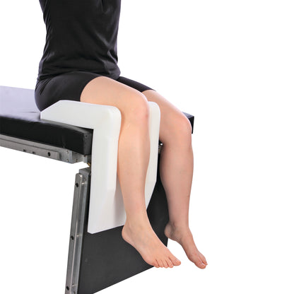 A person sits using the AliMed Arthroscopic Well-Leg Holder, which supports the legs on a cushioned platform attached to a table.