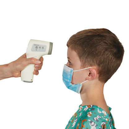 A person uses an IR Thermometer to check the temperature of a child wearing a mask and hospital gown with playful prints.
