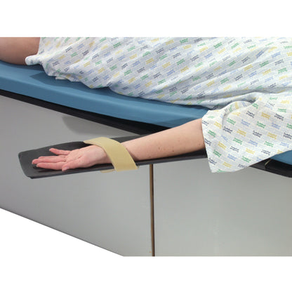A patient on an Angiography Armboard with their arm secured by a strap, lying on a padded hospital table.