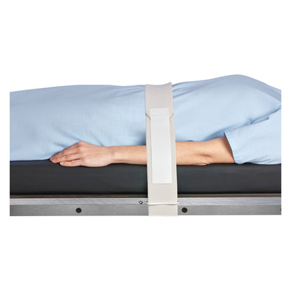 A person lying on a table is secured with a Covidien Devon Disposable Body/Knee Strap, featuring a white strap over a blue gown.