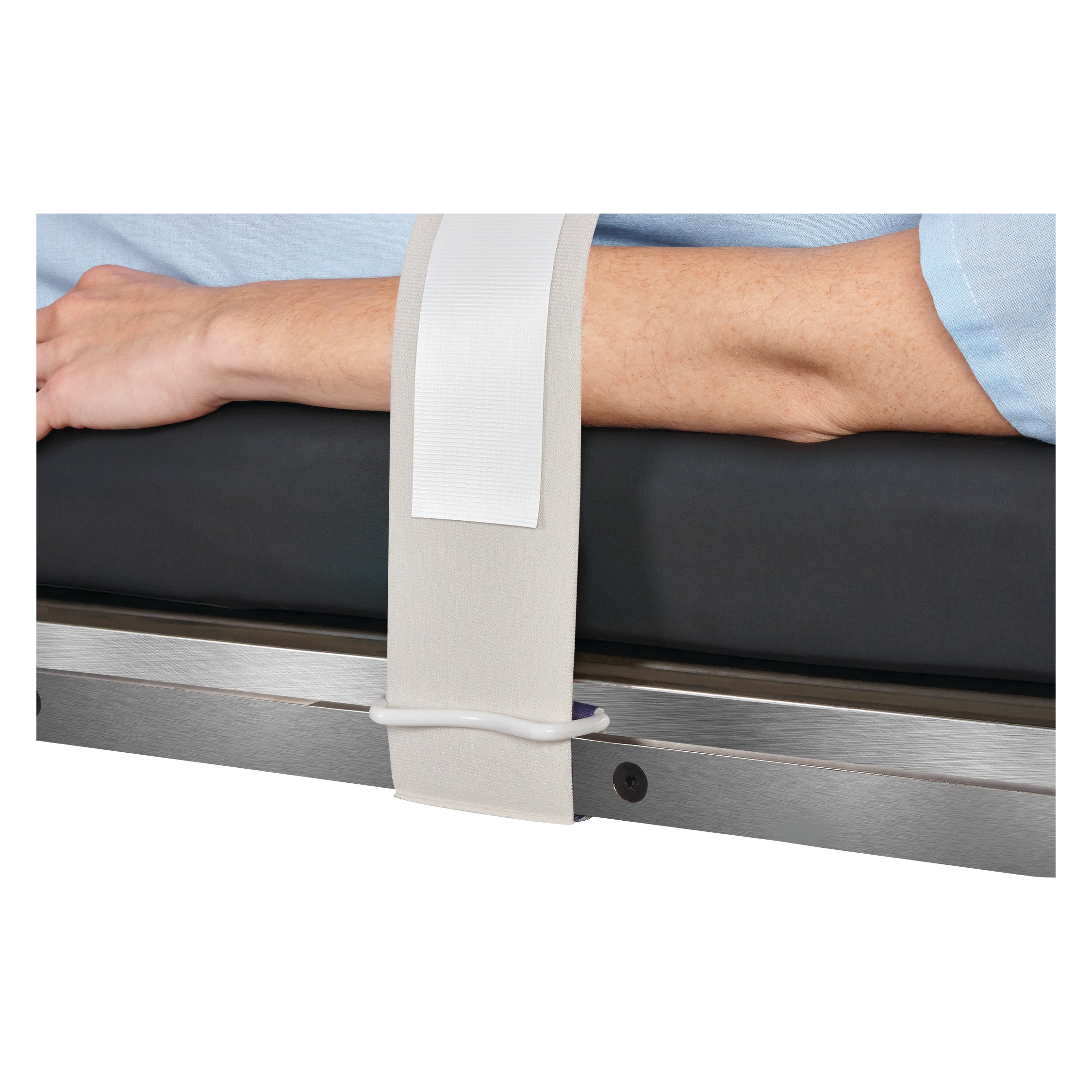 An arm is restrained using a Covidien Devon Disposable Body/Knee Strap on a metal and padded medical table.