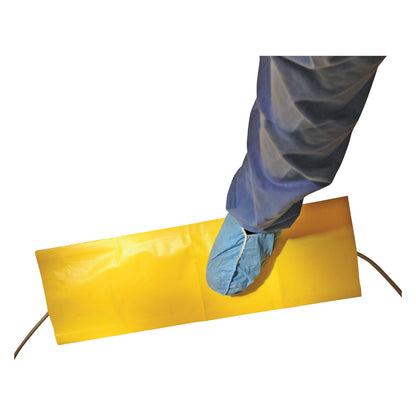 A foot covered with a blue shoe cover steps on a Flagship Surgical Safe Cord Floor Strip, a yellow protective floor strip.
