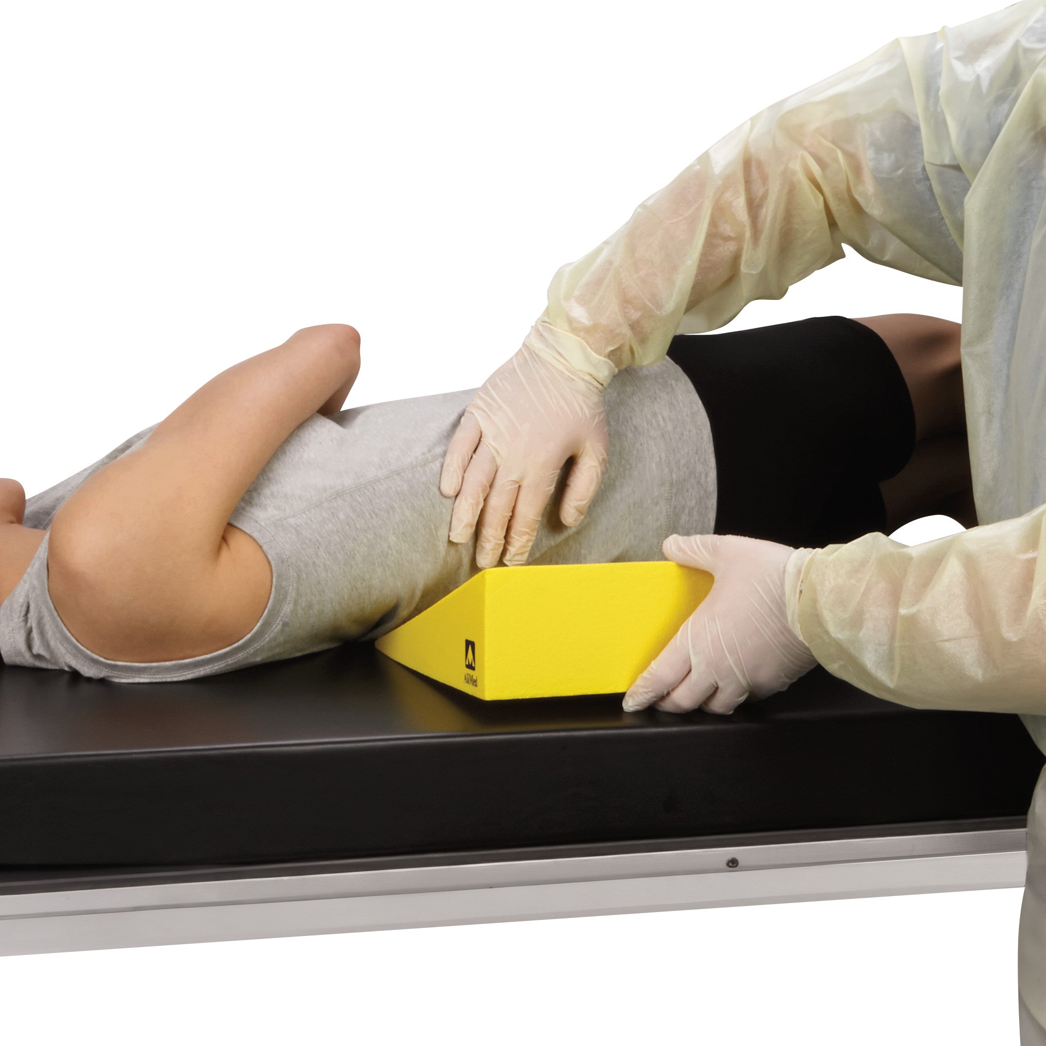 A healthcare worker positions a patient using an AliMed Protecta-Coat 20 Degree Wedge Positioner on an examination table.