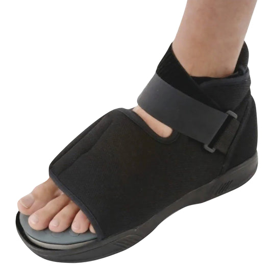 Person wearing an Ossur DH Offloading Post-Op Shoe. The shoe is black, with an open-toe design and adjustable straps.