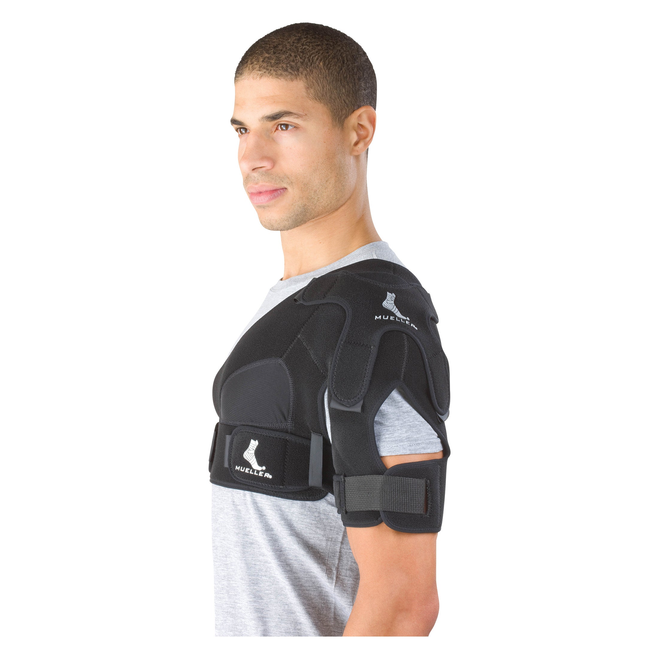 A person wears a Mueller Shoulder Support, a black brace designed to provide stability and support to the shoulder area.
