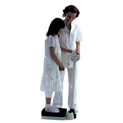 A child stands on a seca 703 Column Scale while an adult assists, both wearing white attire, against a plain background.