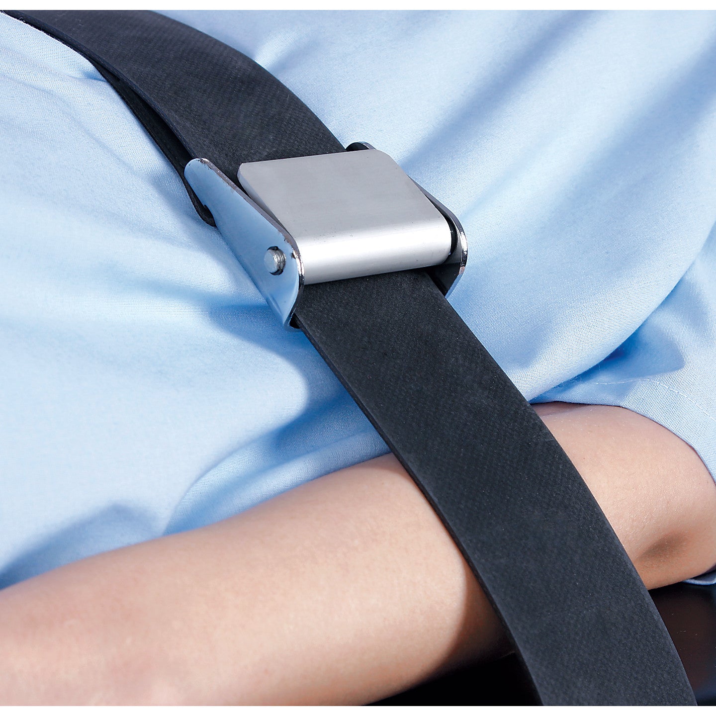 A person is secured with an AliMed Economy Strap across their body, resting on a light blue surface.