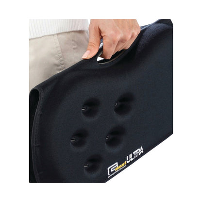 A person holds a black Gelco GSeat Ultra Portable Gel Seat, featuring a handle and indented surface texture.