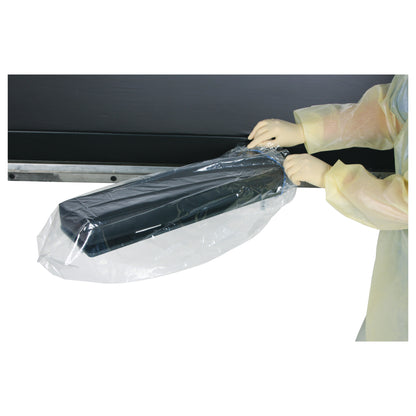 A person wearing gloves uses an AliMed AliBag to cover a black rectangular object, ensuring it's protected by a clear plastic bag.