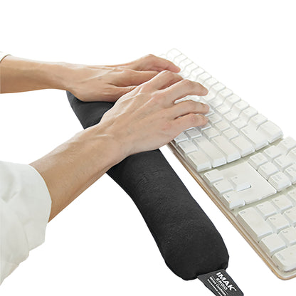 Hands rest on a Brownmed IMAK ergoBeads Keyboard Mouse Cushion placed in front of a white keyboard.