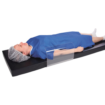 Person lies on a pad with an AliMed Curved Toboggan Arm/Leg Guard over their arm, wearing a blue gown and hair cover.