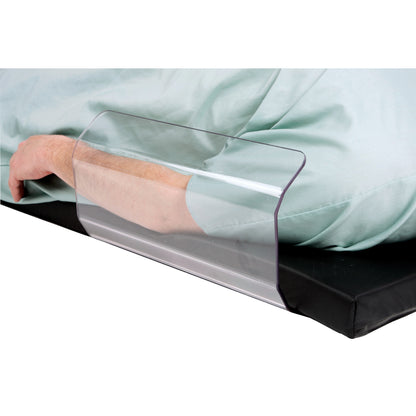 A person's arm is secured by the AliMed Curved Toboggan Arm/Leg Guard, placed on a bed with light green sheets.