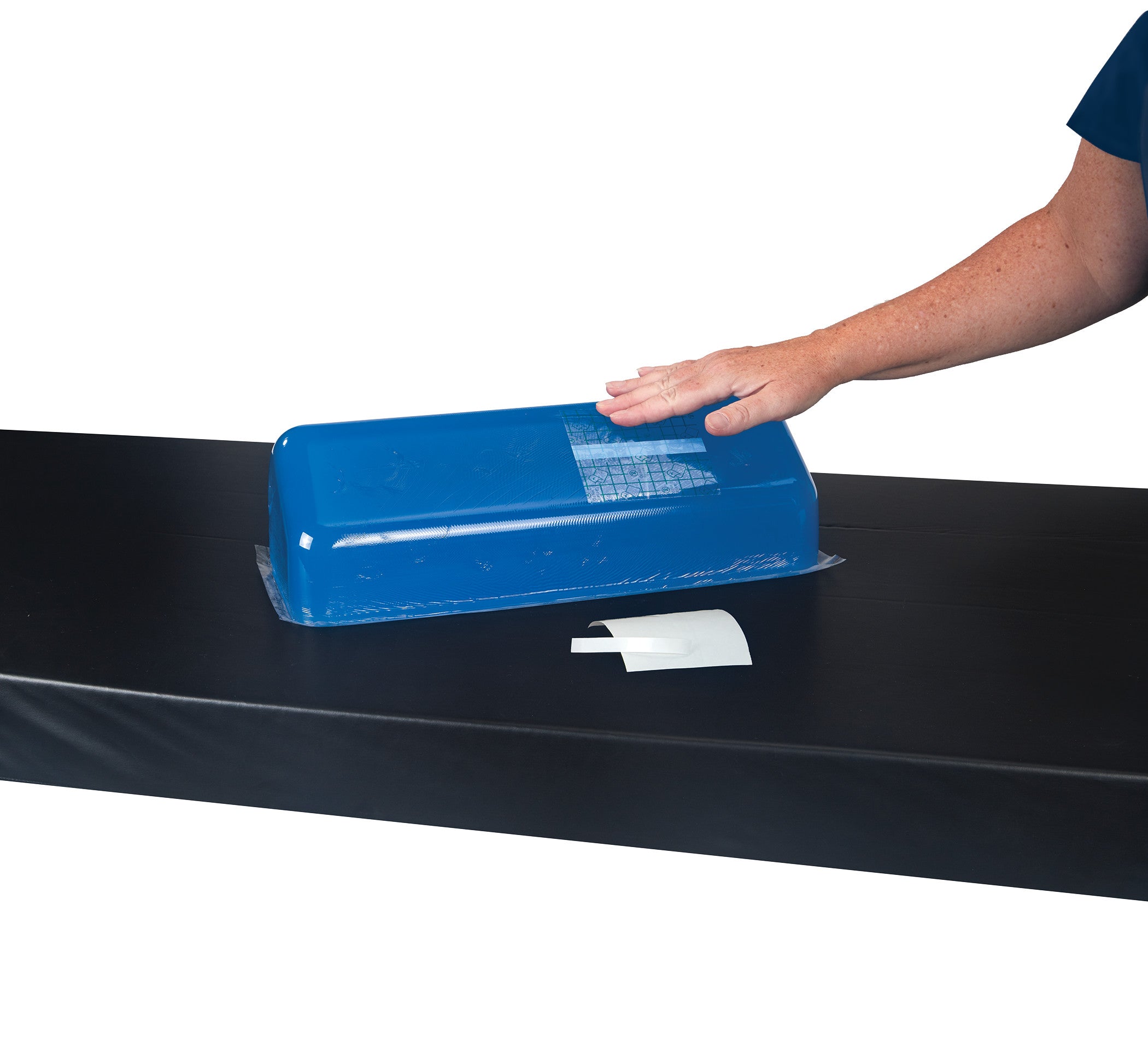 A hand presses down on a blue patch from the AliMed Gel Repair Kit, placed on a black surface with a white card nearby.