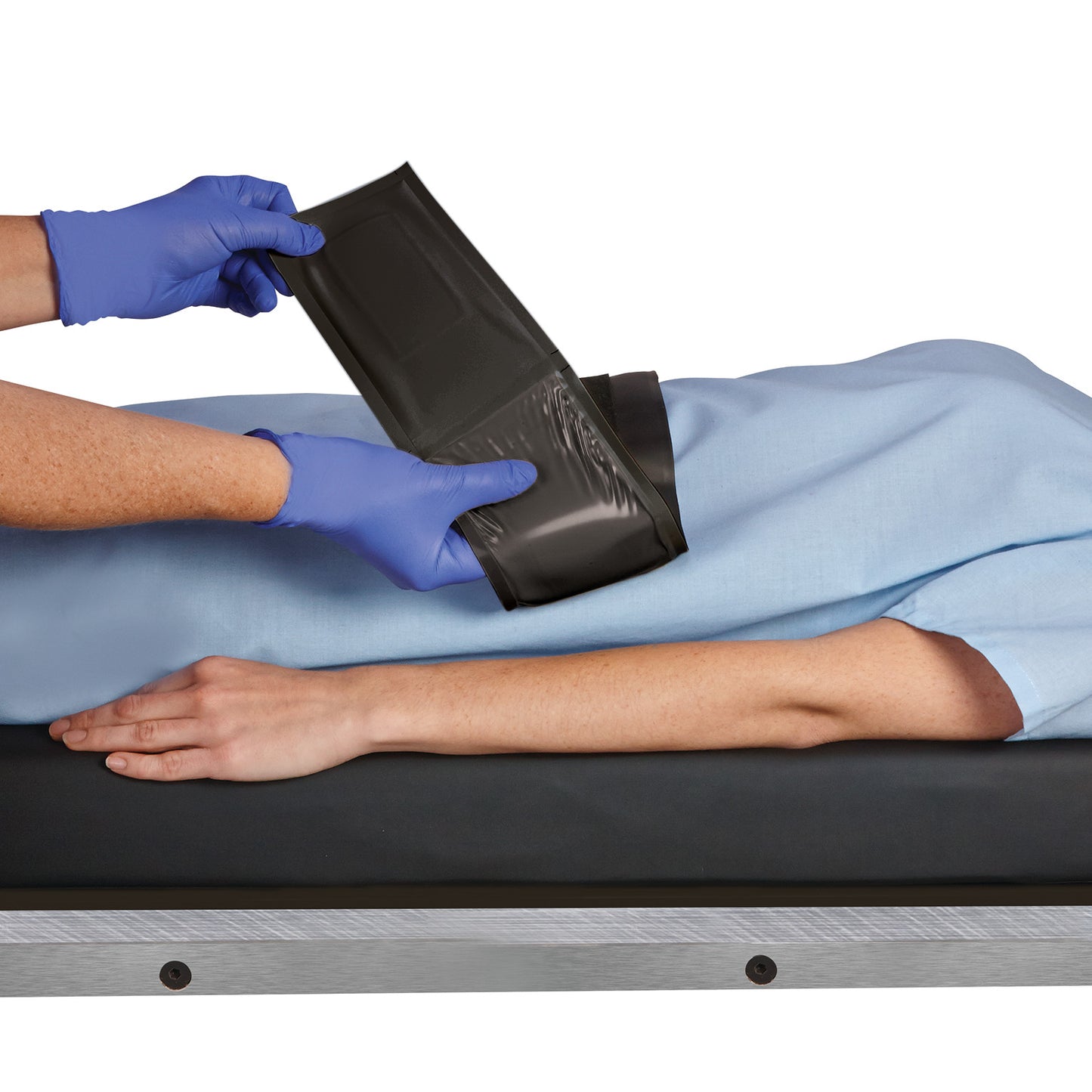 A person fastens an AliMed AliGel Surgical Table Strap over a patient's arm. The strap is black with a yellow gel section.
