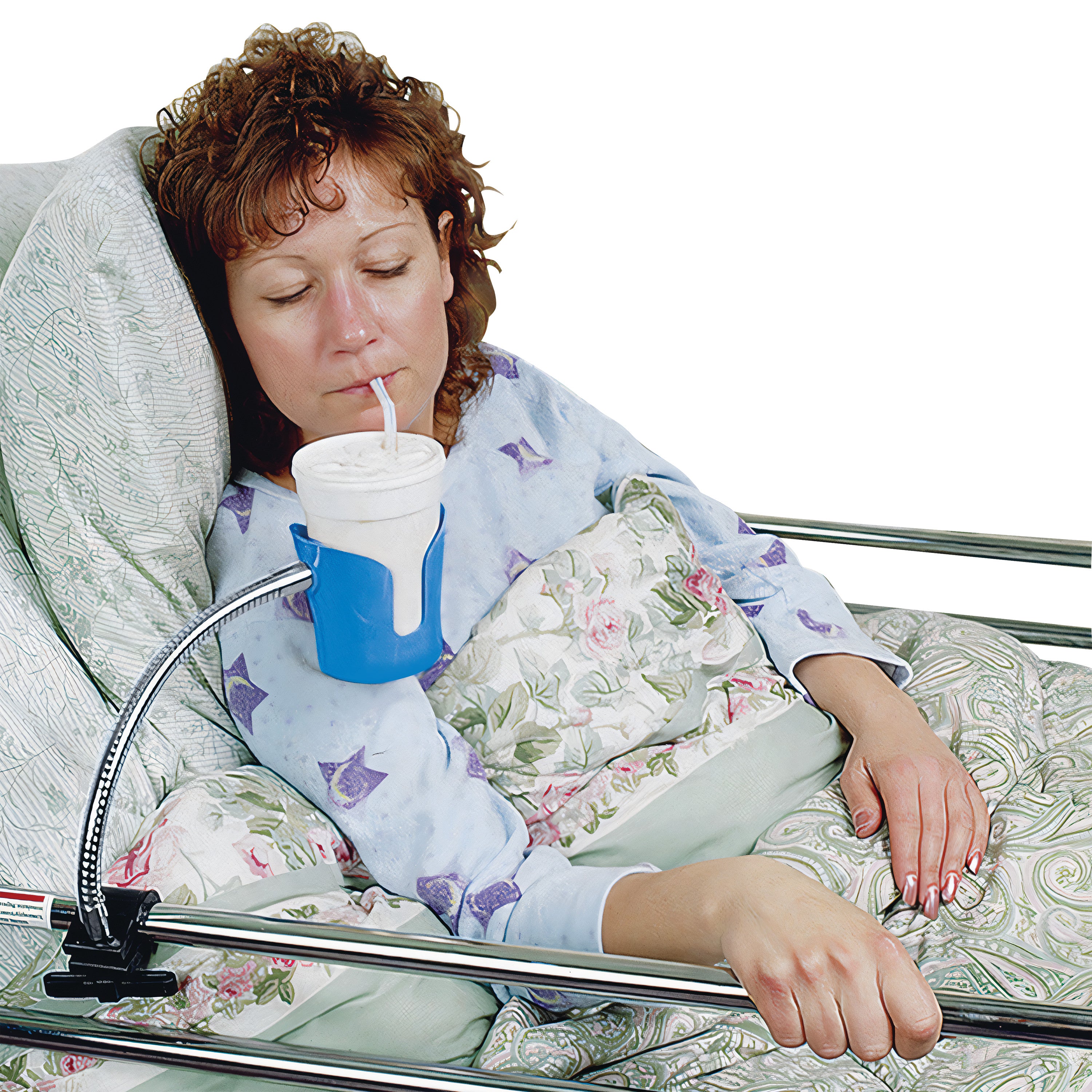 A woman in bed uses a Bedside Beverage Holder to drink from a cup with a straw. The holder is clamped to the bed rail.