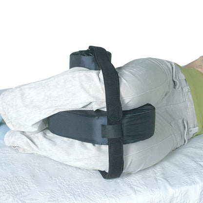 A person lying on their side with a SkiL-Care Side-Lying Leg and Knee Abductor device strapped to their knees for support.