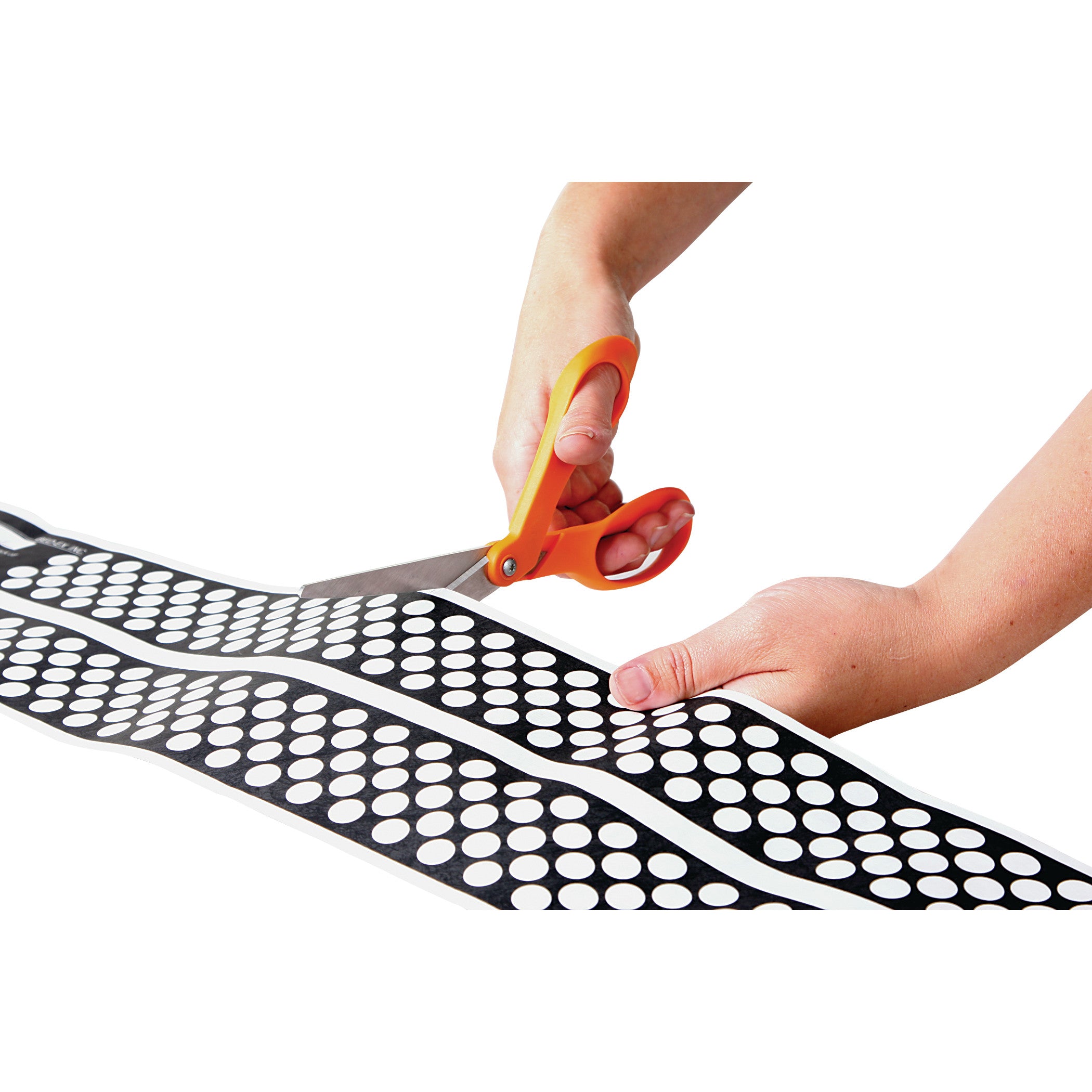 Hands are cutting an AliMed Ultra-Thin Touch-Sensitive Sensor Pad with orange scissors. The pad is black with white dots.