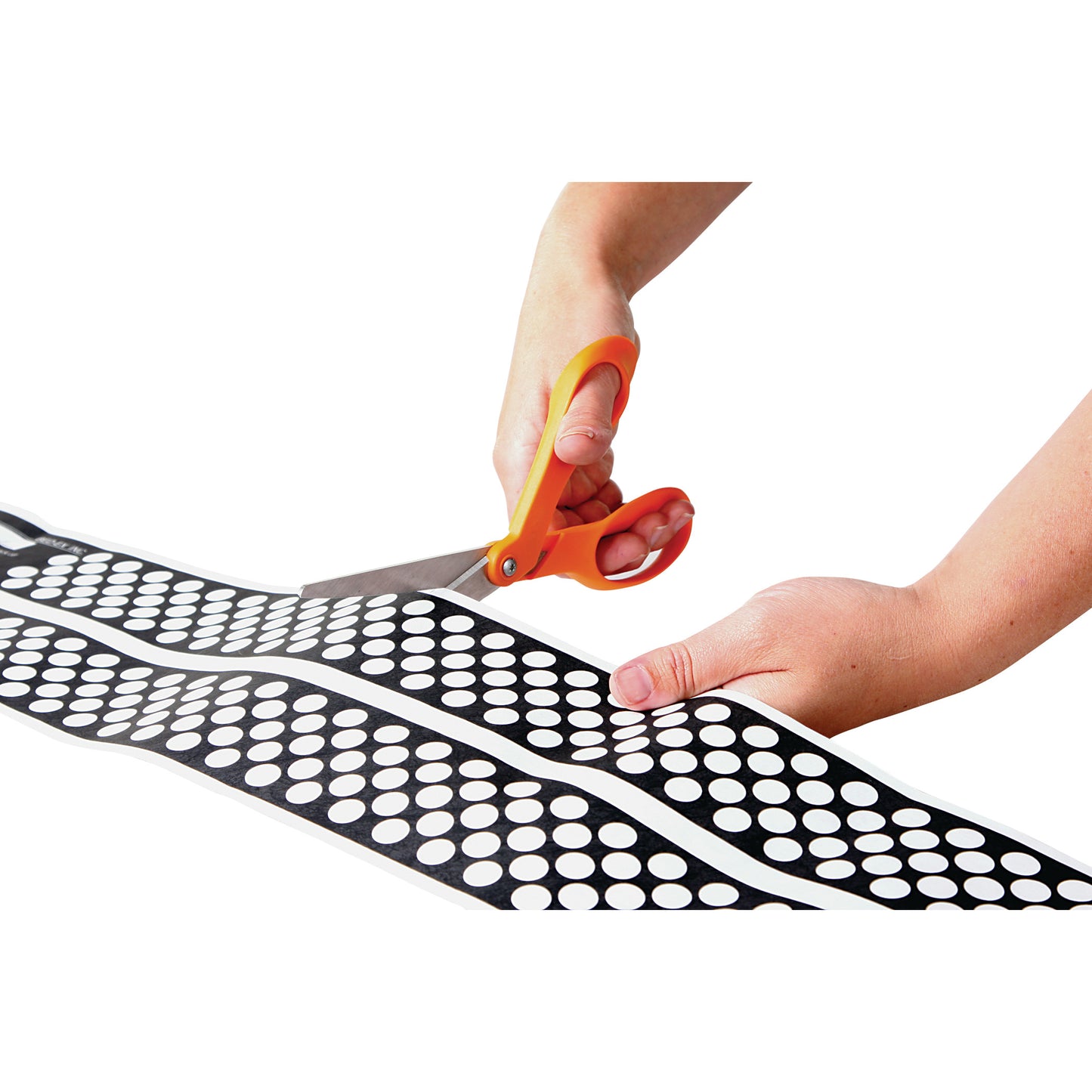 Hands are cutting an AliMed Ultra-Thin Touch-Sensitive Sensor Pad with orange scissors. The pad is black with white dots.