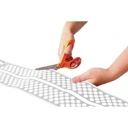 Hands cutting an AliMed Ultra-Thin Touch-Sensitive Sensor Pad with orange-handled scissors against a white background.