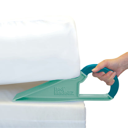 A hand uses the Bed MadeEZ Mattress Lifter to lift a mattress. The device is turquoise and wedge-shaped with a handle.