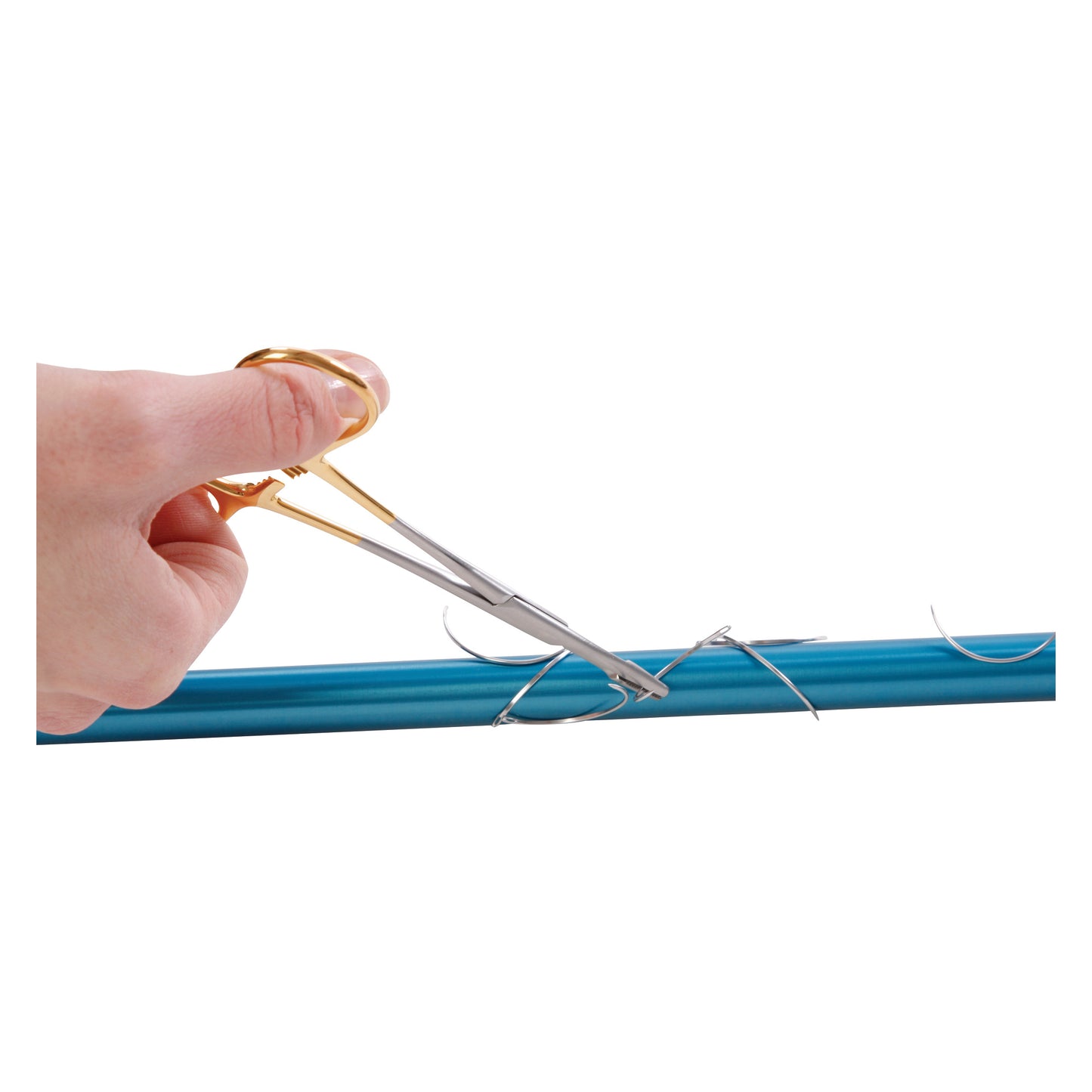 A hand uses the AliMed Low-Profile Magnetic Needle Finder to pick up needles from a blue surface.
