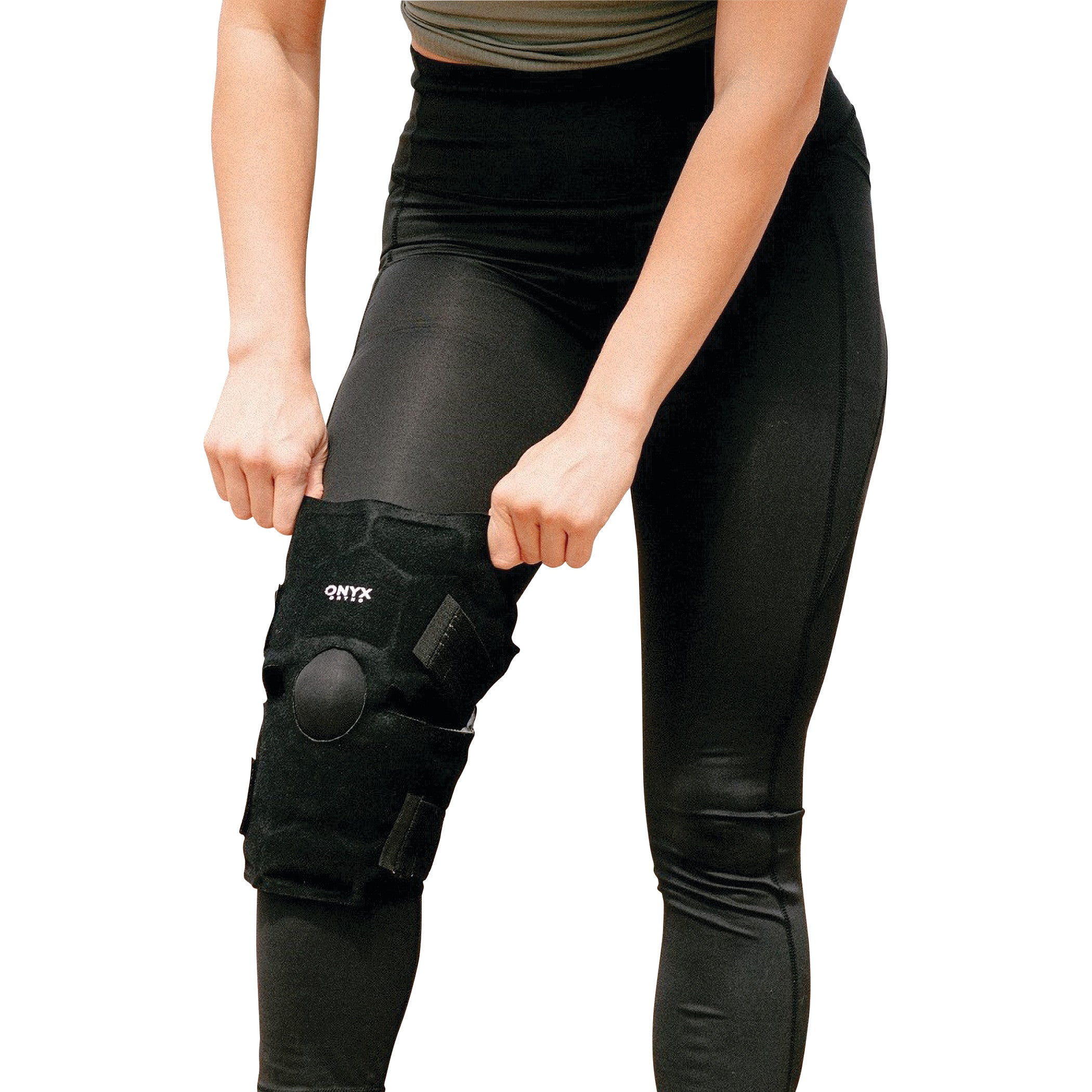 Person adjusting Xena Therapies Onyx Cool Knee brace, wearing black leggings, visible from waist to knee.