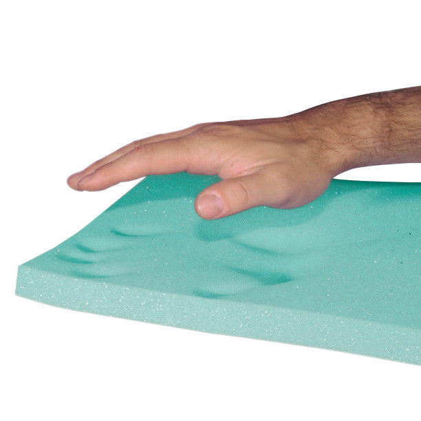 A hand presses on the AliMed T-Foam Uncovered Wheelchair Cushion, creating a visible impression on its green foam surface.