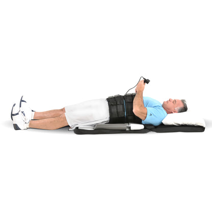 A man lies on a Saunders Lumbar Traction Device, wearing a back brace and holding a control.