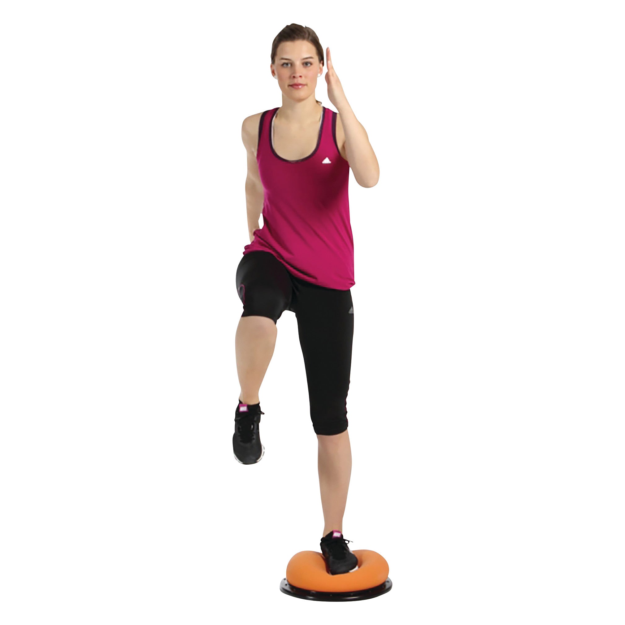 A woman exercises on the TOGU Dynair Pro Ball, balancing on one leg with a raised knee, wearing a pink tank top and black shorts.