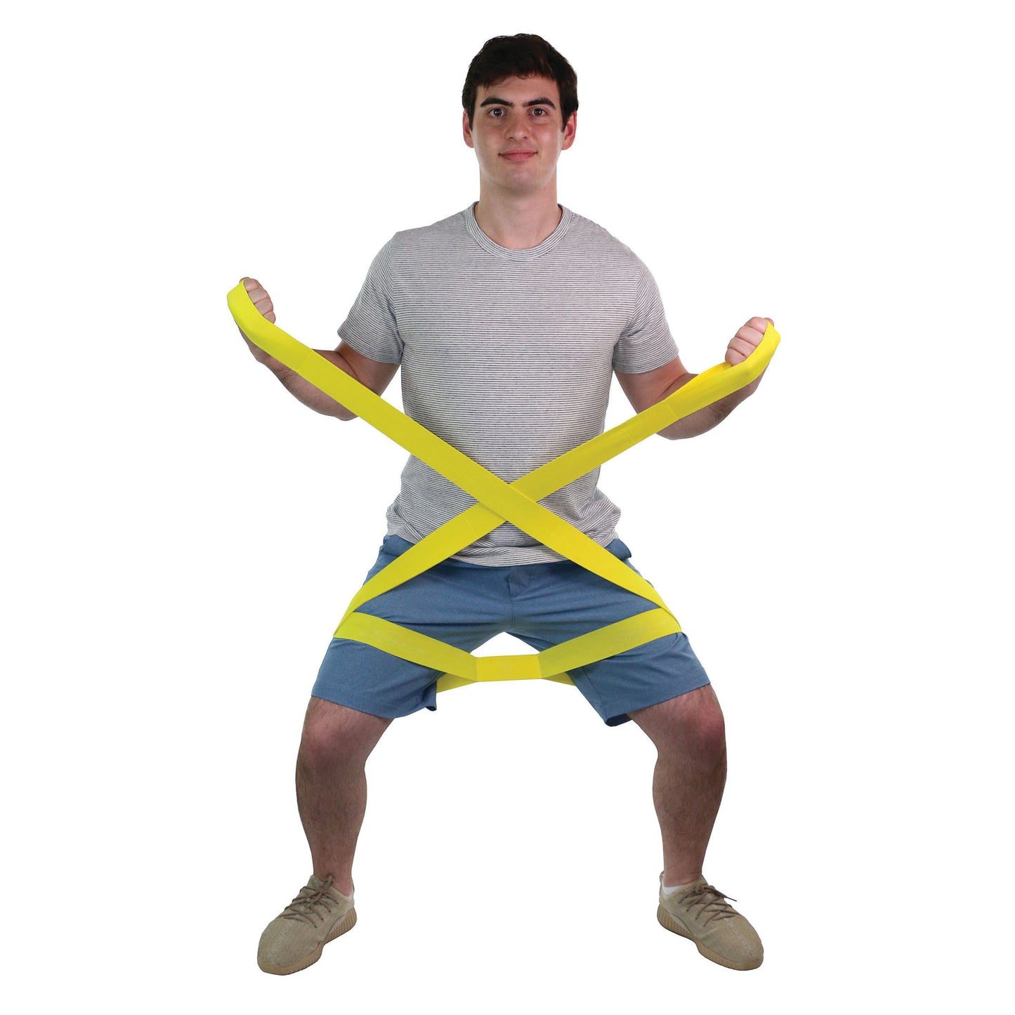 A person squats, holding a yellow CanDo Multi-Grip Exerciser wrapped around their legs and hands for resistance training.