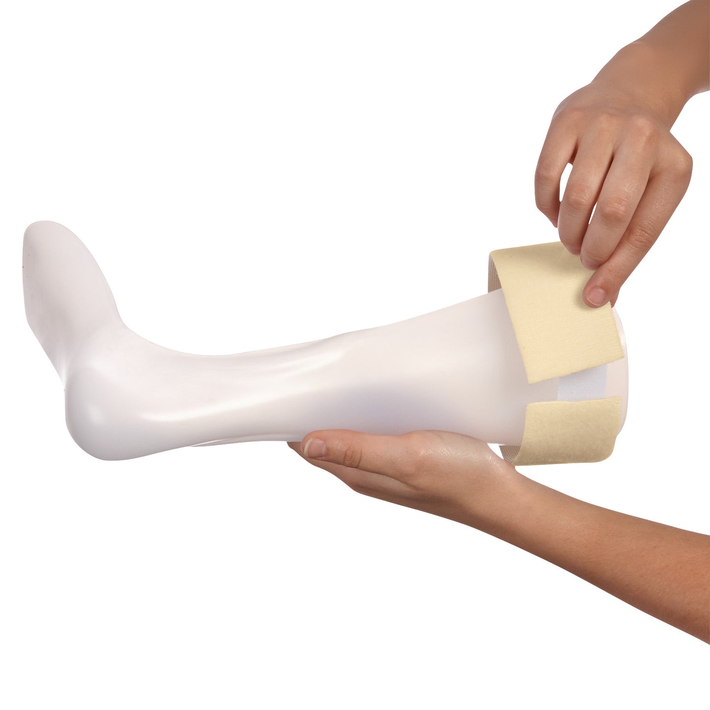 Hands hold a white leg model while applying the AliMed Beta Soft Strap Loop, a beige strap for securing medical devices.