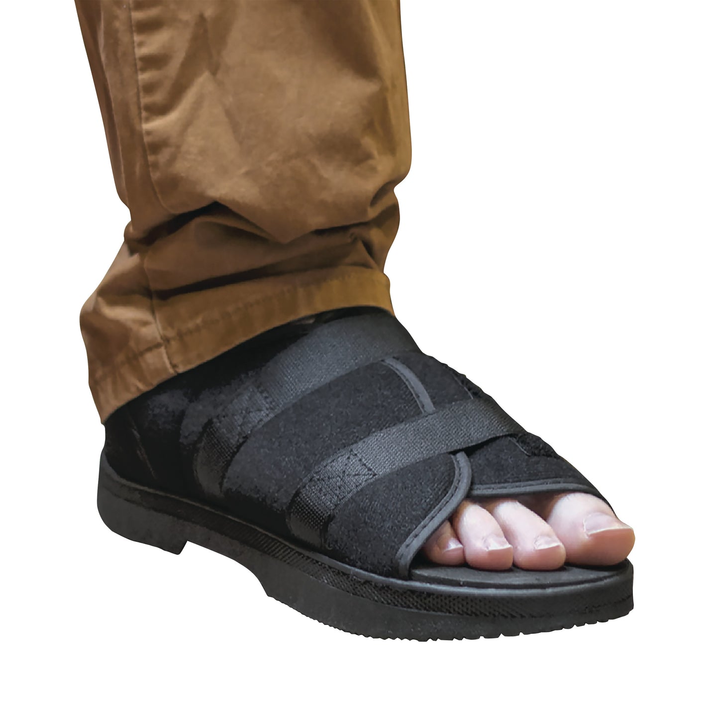 A person wears a DARCO Softie Shoe, an orthopedic shoe with black straps, over brown pants. The toes are exposed.