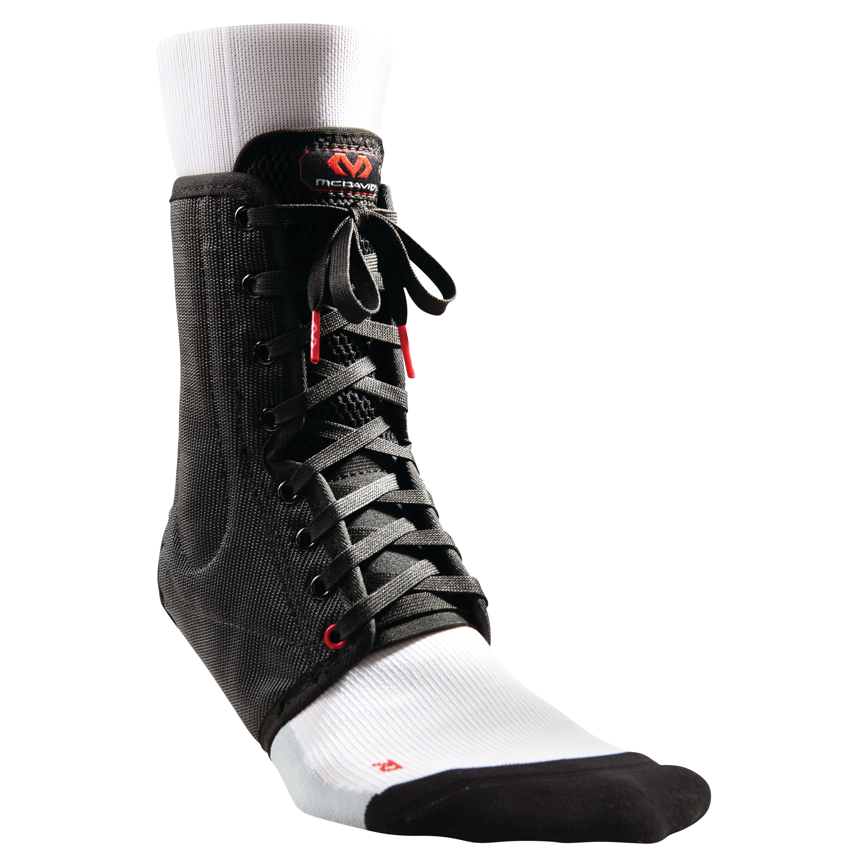 The McDavid Lightweight Laced Ankle Brace in black is worn over a white sock, featuring laces and a red logo at the top.