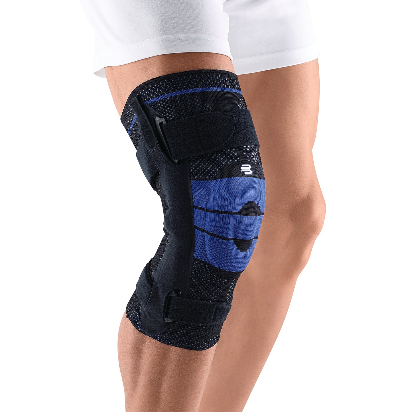 A person wears a Bauerfeind GenuTrain S Knee Brace on the left knee, featuring blue fabric and adjustable black straps.