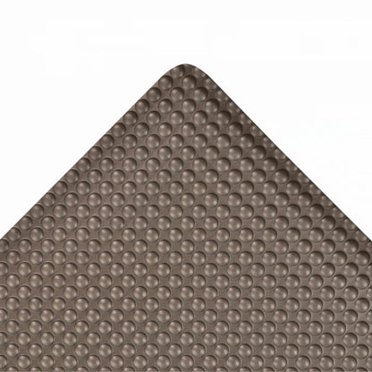 Corner view of the Bubble Trax Anti-Fatigue Mat with a textured, raised dome pattern on a brown surface.