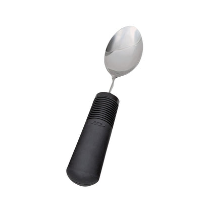 A Good Grips Standard Utensils spoon with a stainless steel head and a thick, black, non-slip handle featuring grip ridges.