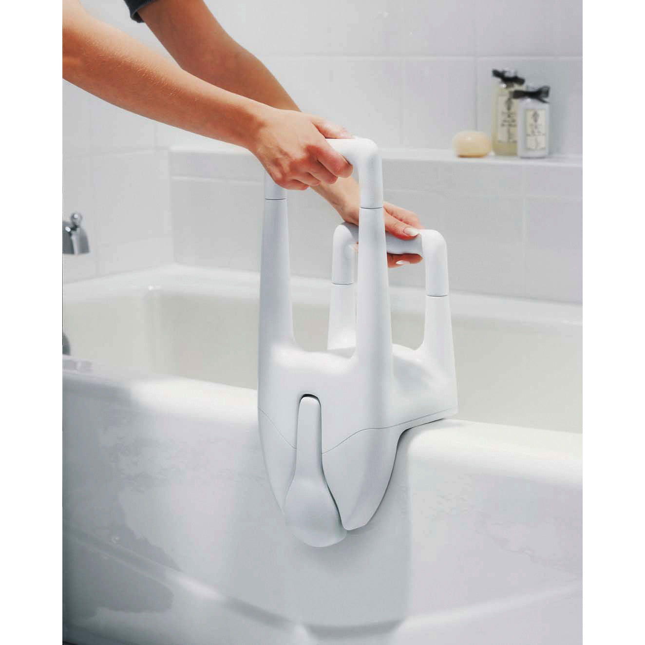 A person adjusts a Moen Dual Tub Grip, a white safety handle installed on the edge of a bathtub for stability and support.