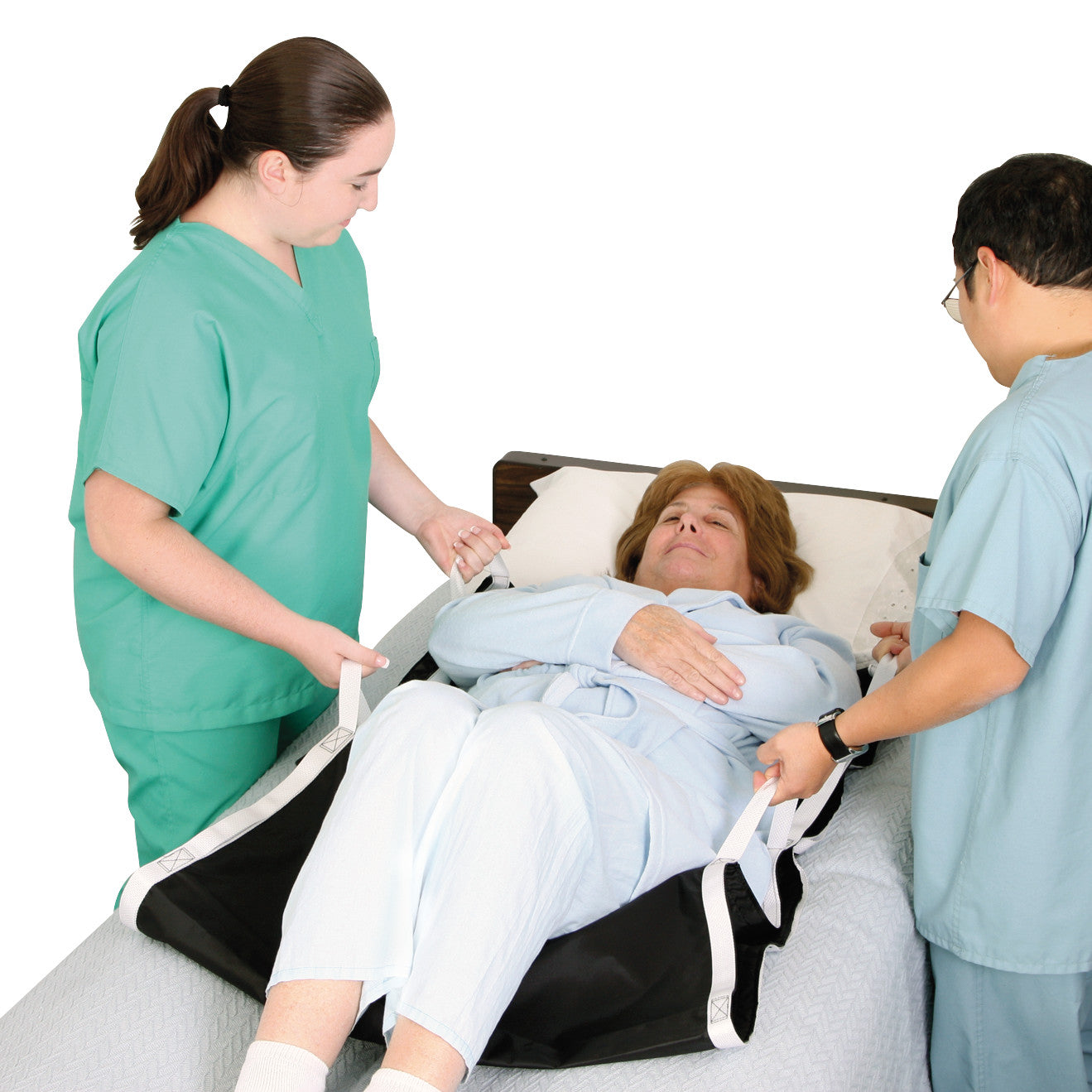 Two healthcare workers assist a patient on a bed using the AliMed No-Lift BOOSTER to reposition her comfortably.