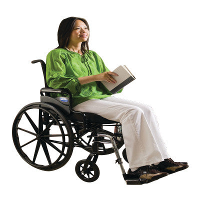 A woman sits in an Invacare 9000XT Wheelchair with Adjustable Desk Arms and Swing-Away Footrests, holding a book.