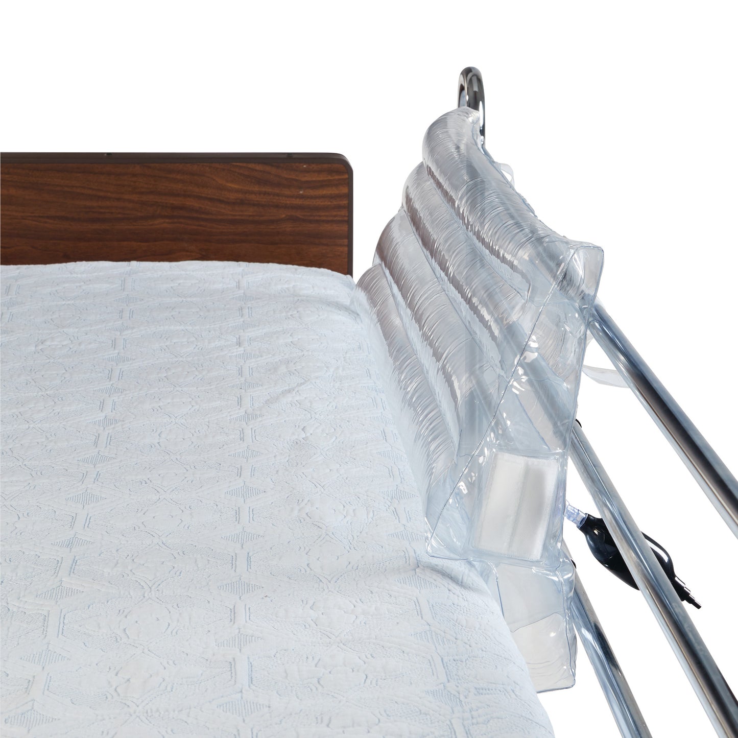 A bed with a white textured sheet and an AliMed Clear Inflatable Bed Bolster attached to a metal bed rail on the side.