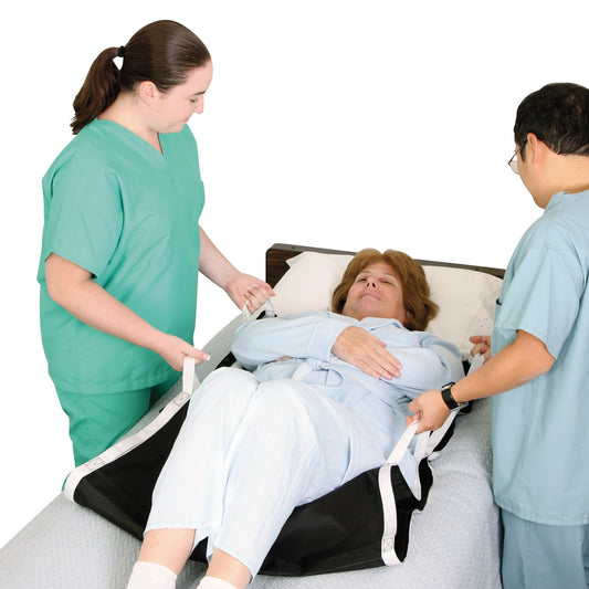 Two caregivers use the AliMed No-Lift BOOSTER to assist a patient in a hospital bed, lifting with straps under the patient.