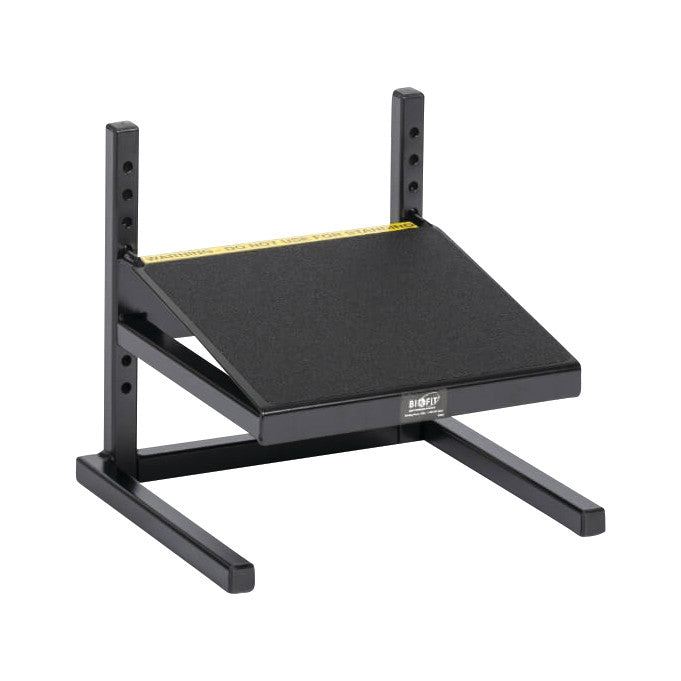 The BioFit Factory Footrest is a black adjustable footrest with a textured surface and a yellow warning label along the top edge.