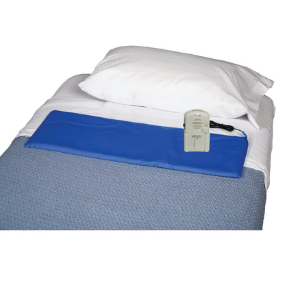 A bed equipped with an AliMed IQ VOICE Alarm with Bed Sensor Pad on a blue quilted blanket, connected to a control device.